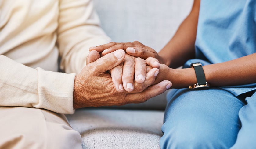 Portrait of a nurse's hands holding an older man's hands